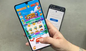 Dłoń trzymająca smartfon z grą Coin Master, obok drugi telefon z PayPal.