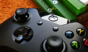 Czarny kontroler Xbox i zielone pudełka z grami. Idealny zestaw do wspólnej zabawy w gry survival multiplayer.