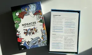 Pudełko gry fabularnej "Nosacze" z kolorowymi ilustracjami i otwartą instrukcją.
