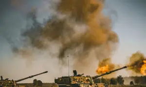 Dwa czołgi strzelają, tworząc kłęby dymu i ognia. Scena wygląda jak ćwiczenia, ale można by pomyśleć o "friendly fire".