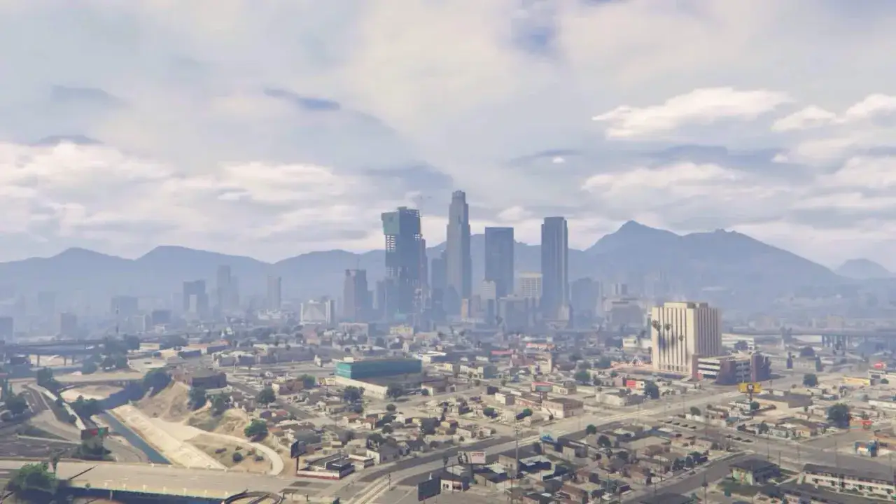 Rozległa panorama miasta Los Santos z górami w tle. Chmury na niebie.