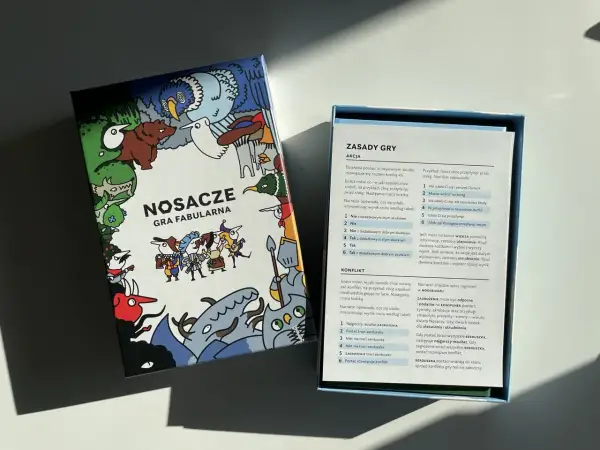 Pudełko gry fabularnej "Nosacze" z kolorowymi ilustracjami i otwartą instrukcją.