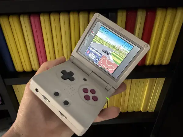 Gra wyścigowa na ekranie konsoli Game Boy Color, trzymanej w dłoni.